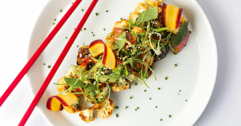Plated vegetables and protein garnished with greens