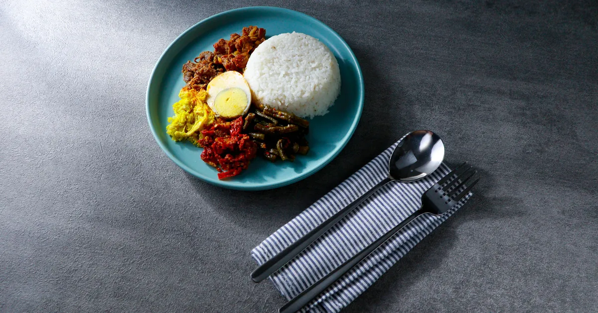 Plate of rice, egg and vegetables with a place setting