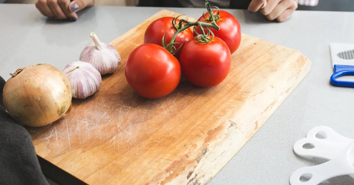 Tomatoes, onion and garlic on a wooden cutting board