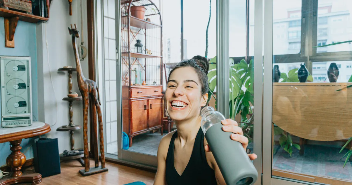 Woman holding up a reusable water bottle to drink