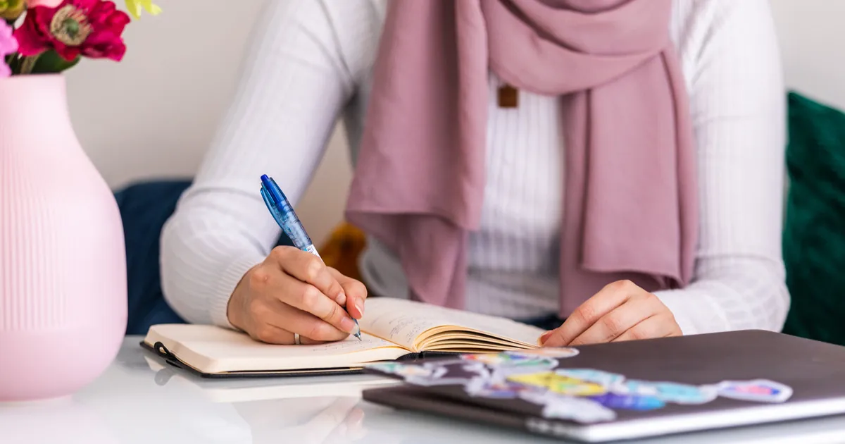 Woman writing notes in a journal at a table